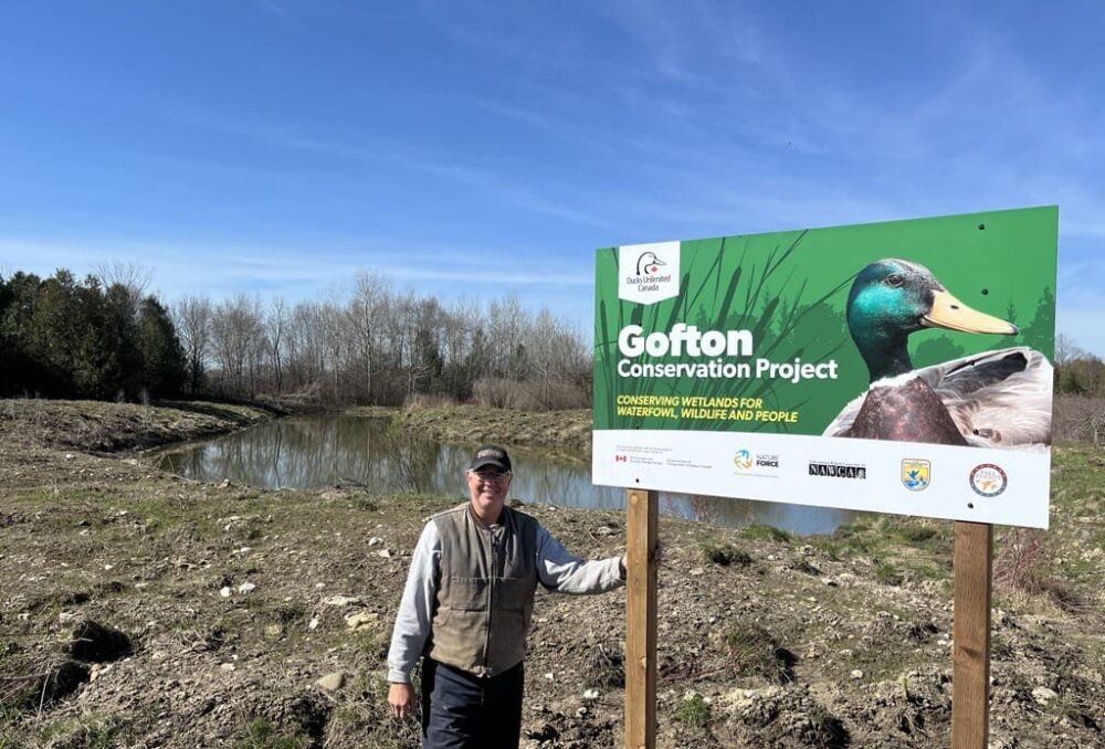 Landowner Randy Gofton in front of his new wetland and sign.