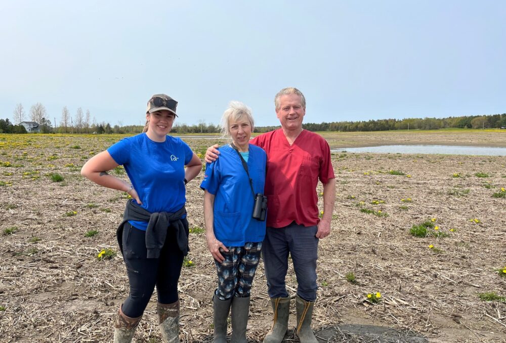 Landowners Barb and Paul O'Neill in front of their new wetland with DUC conservation program specialist, Mikayla Stinson.