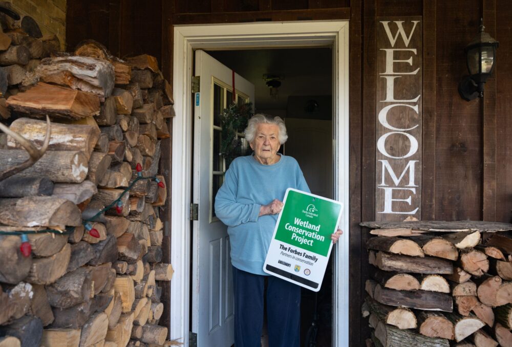 Ethel Forbes holding her DUC sign in her doorway.